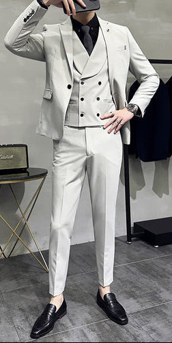 Man wearing a light gray suit taking a mirror selfie in a stylish setting.